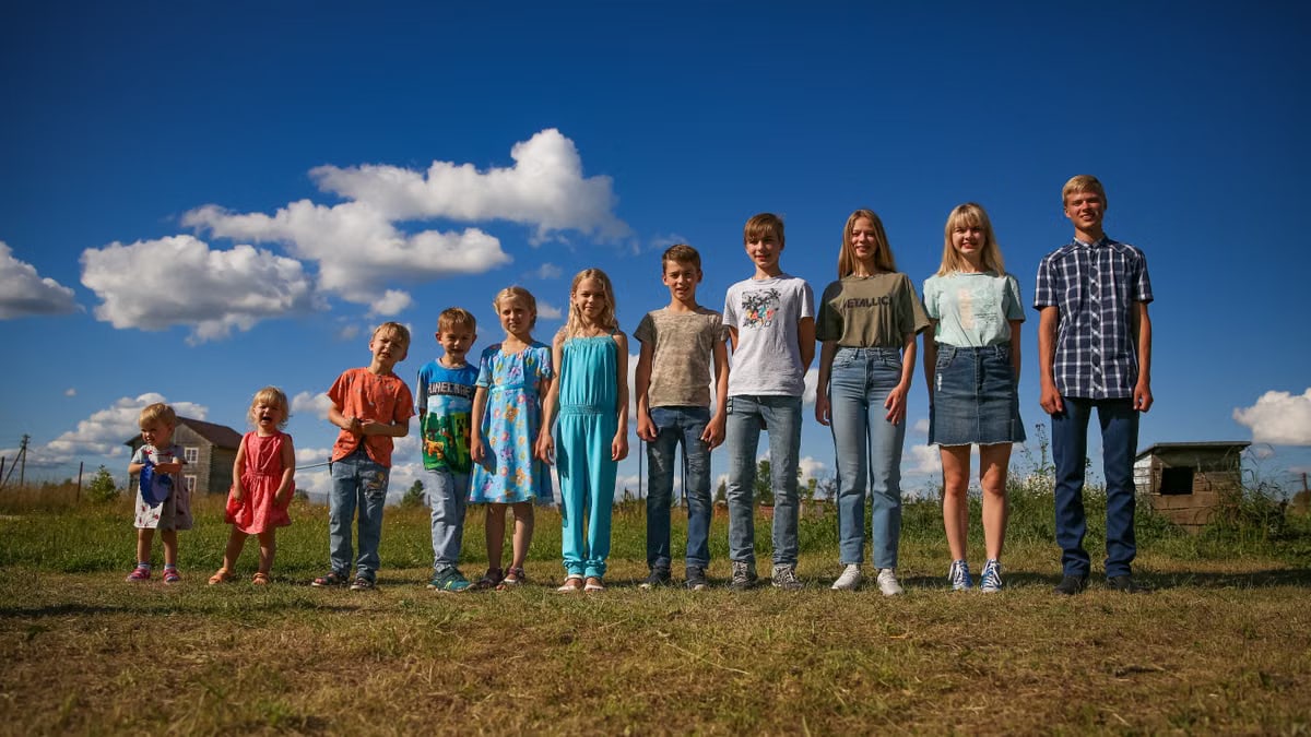 A diverse group of children and teenagers smiling under a sunny blue sky, showcasing unity and happiness.